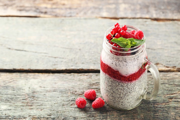 Chia pudding with berries in glass jar on wooden table