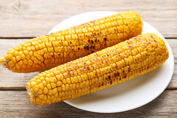 Tasty grilled corns on grey wooden table