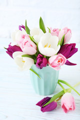 Bouquet of tulips in cup on brick wall background