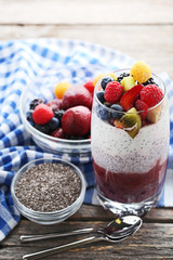 Chia pudding with berries in glasses on grey wooden table