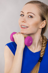Teenage woman working out at home with dumbbell
