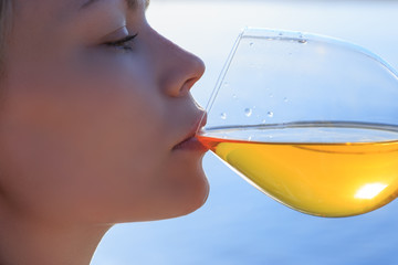 Closeup young beautiful woman is drinking white wine celebrating anniversary outdoors  at the  sea background.