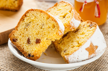 homemade traditional fruit cake slices at white plate decorated with raisins on wooden table top view