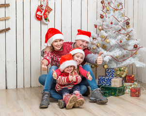 big family in red santa hats near the christmas tree 