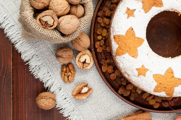 homemade traditional fruit cake on clay plate decorated with raisins and nuts at wooden table top view