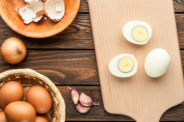 boiled chicken eggs at cutting board decorated with food ingredients on wooden table