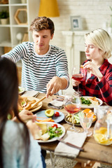 Group portrait of  young friends having dinner together, gathered at big table with delicious dishes on it