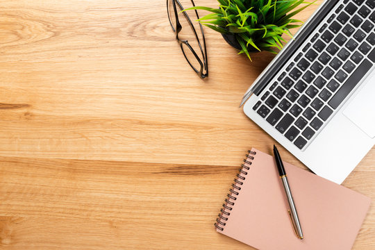 Notepad and laptop on wooden table