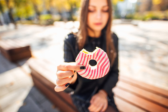 Young girl eat donut in park autumn background