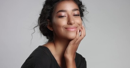 Calm confident and healthy young girl with beautiful glowing skin sitting and playing with camera on white background