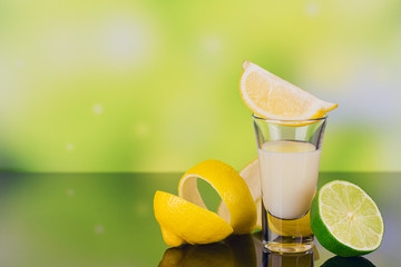 Glasses of cream liqueur with lime and lemon on green background with reflection.