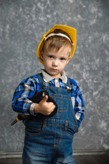 Boy in hard hat with drill, screwdriver in hand