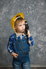 Boy in hard hat with drill, screwdriver in hand