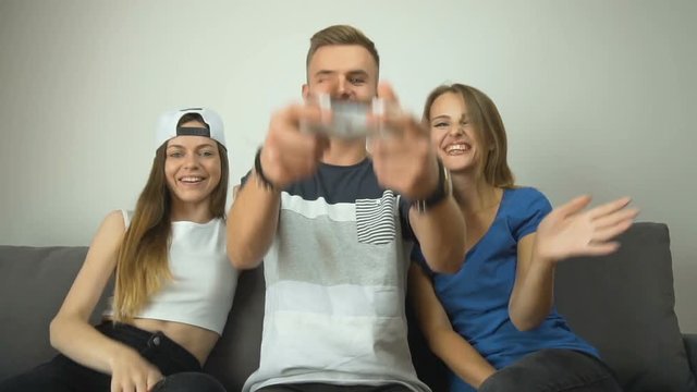 Cute caucasian teenagers have fun, playing video games on the comfortabe sofa, slow motion