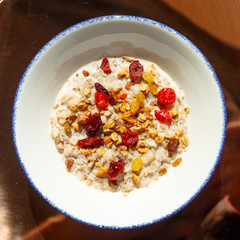 Oatmeal with granola and dried berries lying on the plate. Sunny morning, Breakfast