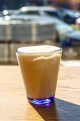 Cappuccino coffee is poured into a glass. Sunny morning, Breakfast
