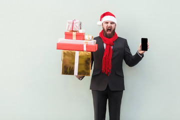 Anger businessman holding on hands gift box and phone. Looking at camera with roar face.