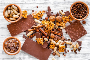 Cook homemade chocolate. Chocolate bars, nuts, sugar, coffee beans, cinnamon on grey wooden background top view