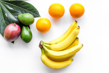 Tropical fruits background. Mango near exotic leaf, banana and pineapple on white top view copyspace