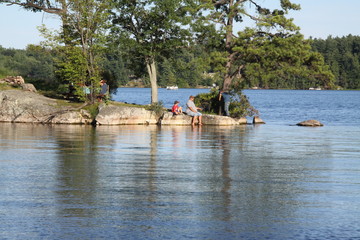 Father and Son fishing from a rocky area above the shore of a big lake.  