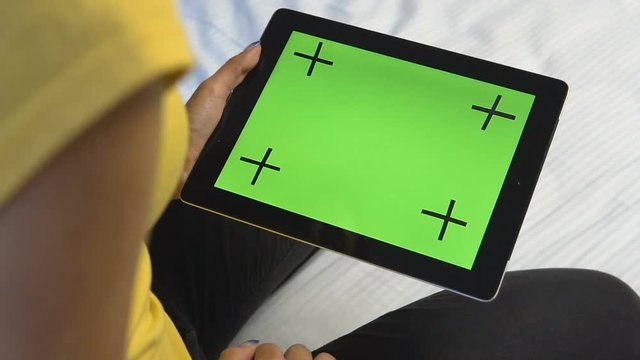 Young caucasian girl touching the green screen of her tablet, slow motion