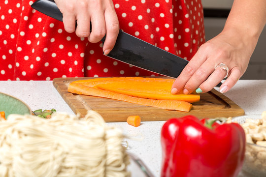 Woman cutting carrot on wooden board