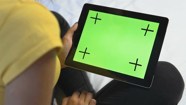 Young caucasian girl touching the flat green screen of her tablet, slow motion