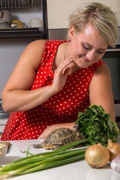 Girl smiles and observes tortoise who is eating roman salad