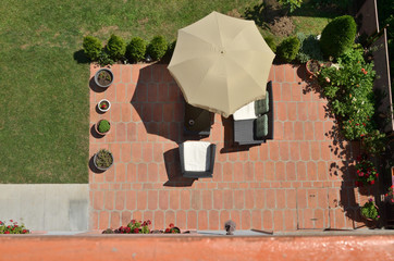 Bird's eye view of garden furniture under parasol surrounded by garden plants © branislav