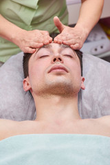 Handsome man getting face massaged. Work of a masseuse.