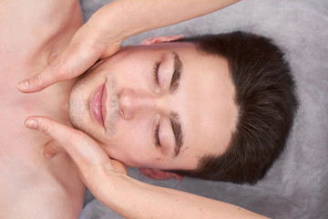 Fototapeta na wymiar Face massage, handsome man. Hands of masseuse. Massage tips from professionals.