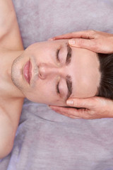 Fototapeta na wymiar Young man, facial massage. Female hands massaging face.