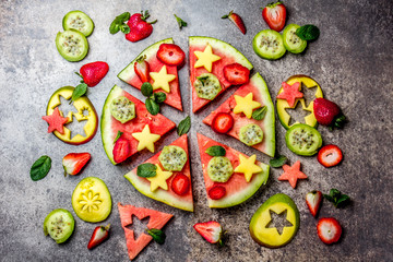 Fruit watermelon pizza with tropical fruits and berries - mango, tuna and mint on stone gray background. Pizza made of watermelon and fruits, top view