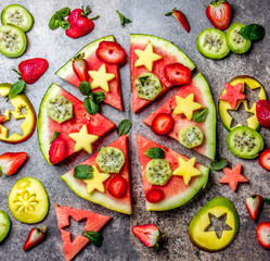 Fruit watermelon pizza with tropical fruits and berries - mango, tuna and mint on stone gray background. Pizza made of watermelon and fruits, top view