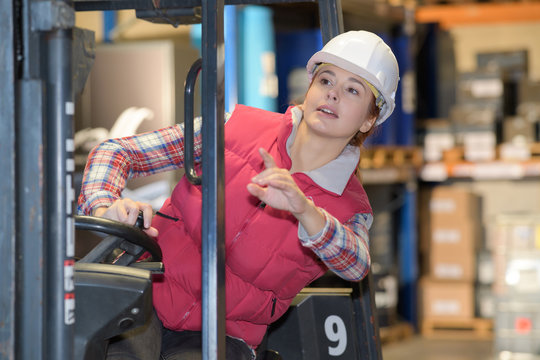 young woman driving a reach truck in a warehouse