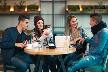 Group of young people sitting in a coffee shop having fun