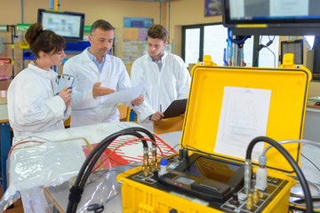 People in workshop, electrical powerpack in foreground