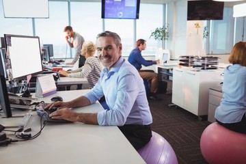 Portrait of smiling businessman working at desk while sitting on