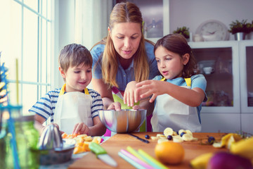 Cute kids with mother preparing a healthy fruit snack in kitchen 