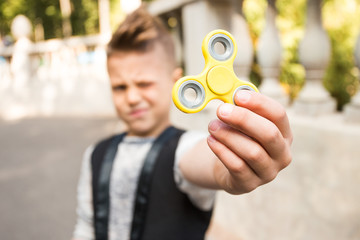Close up portrait of beautiful boy with yellow spinner and smile. Happy and fun child playing with...