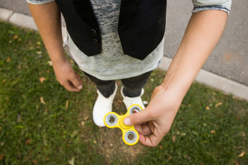 Close up. Boy's hands with spinner. Casual beautiful boy in style clothes with spinner