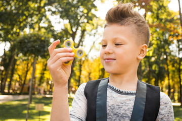 Close up portrait of beautiful boy with yellow spinner and smile. Happy and fun child playing with...