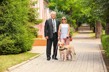Man and blind woman with guide dog in the city