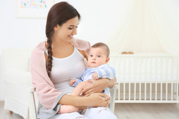 Mother and cute baby sitting on chair after bathing at home