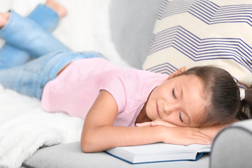 Obraz na płótnie Canvas Cute little girl sleeping on sofa with book