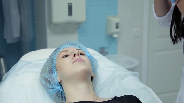 In the beauty salon the doctor-cosmetologist injects Botox into the girl's lips. The process of lip augmentation