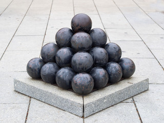 old black  iron cannon balls arranged in pyramid shape