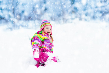 Child playing with snow in winter. Kids outdoors.