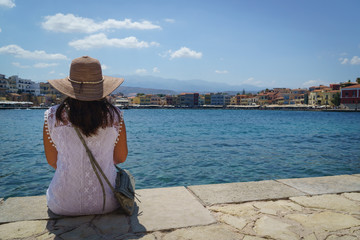Rear view of woman sitting on a pier near of Chania, Greece,