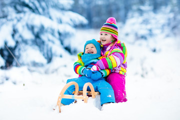 Kids on sleigh ride. Children sledding. Winter snow fun.